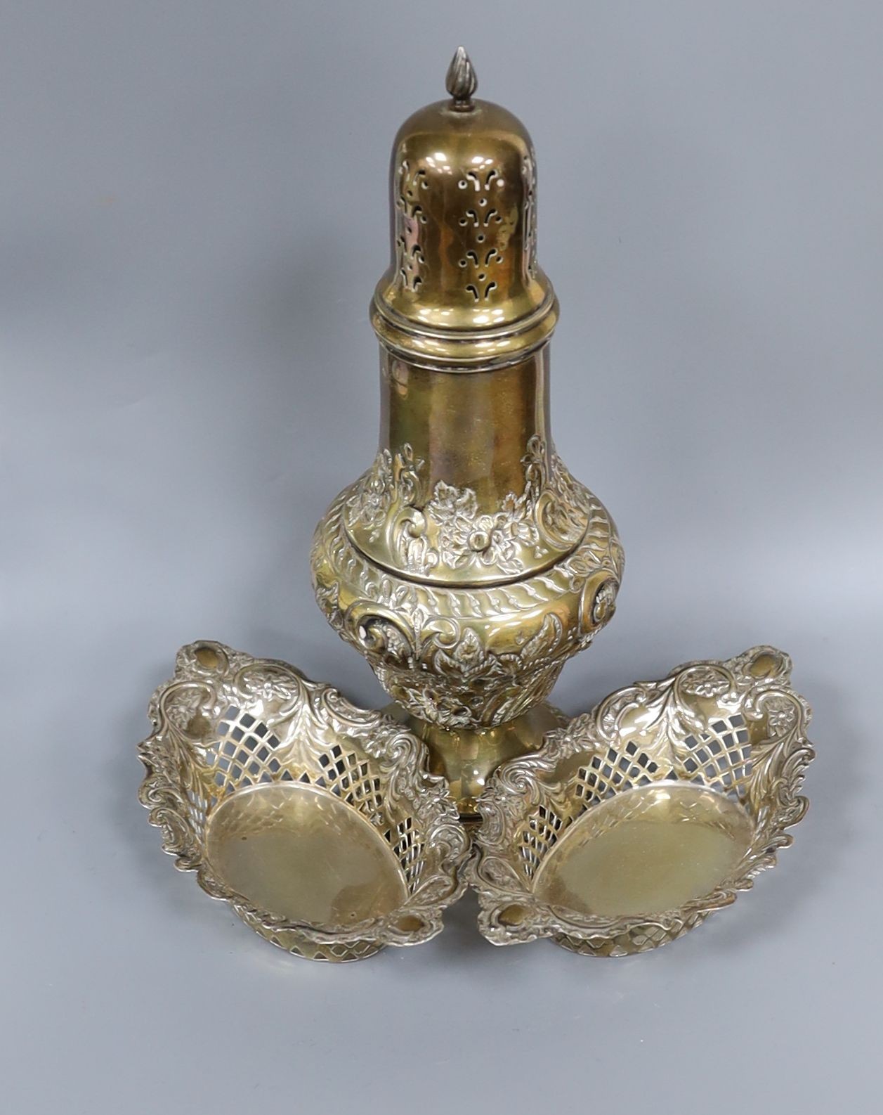 An Edwardian silver sugar caster, 23.8cm and a pair of pierced silver bonbon dishes, 11.5oz.